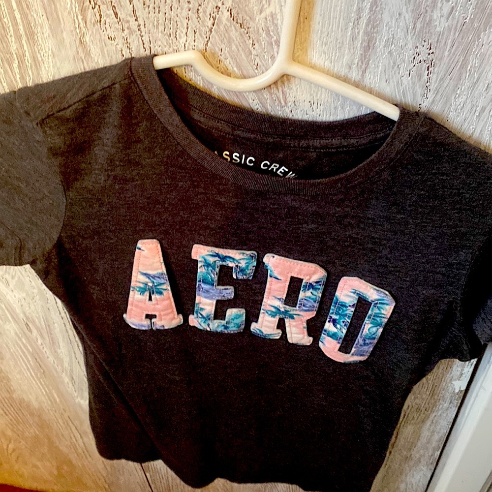 Light grey shirt sleeve T-shirt. Pink with palm trees lettered.
